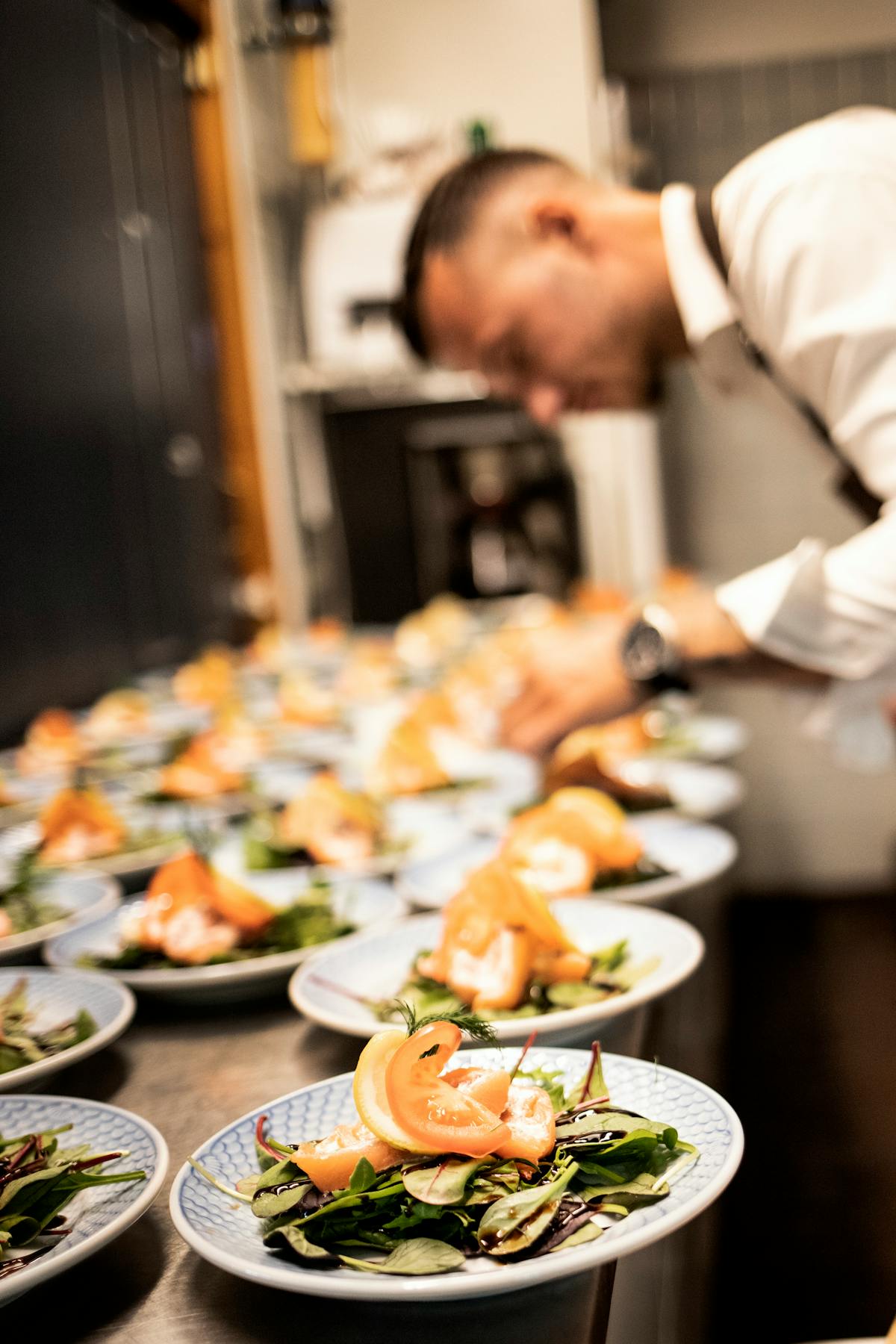 Chef arranging elegant salmon salads in a professional restaurant kitchen
