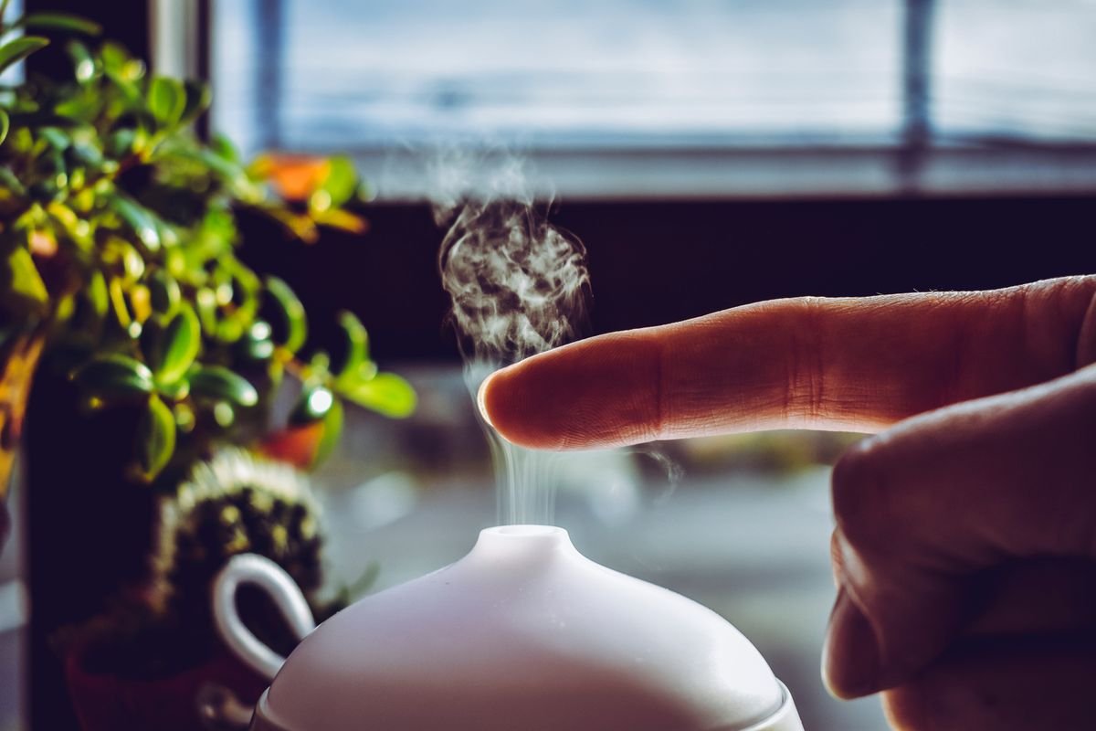 A hand passing through the mist rising from an aromatherapy diffuser
