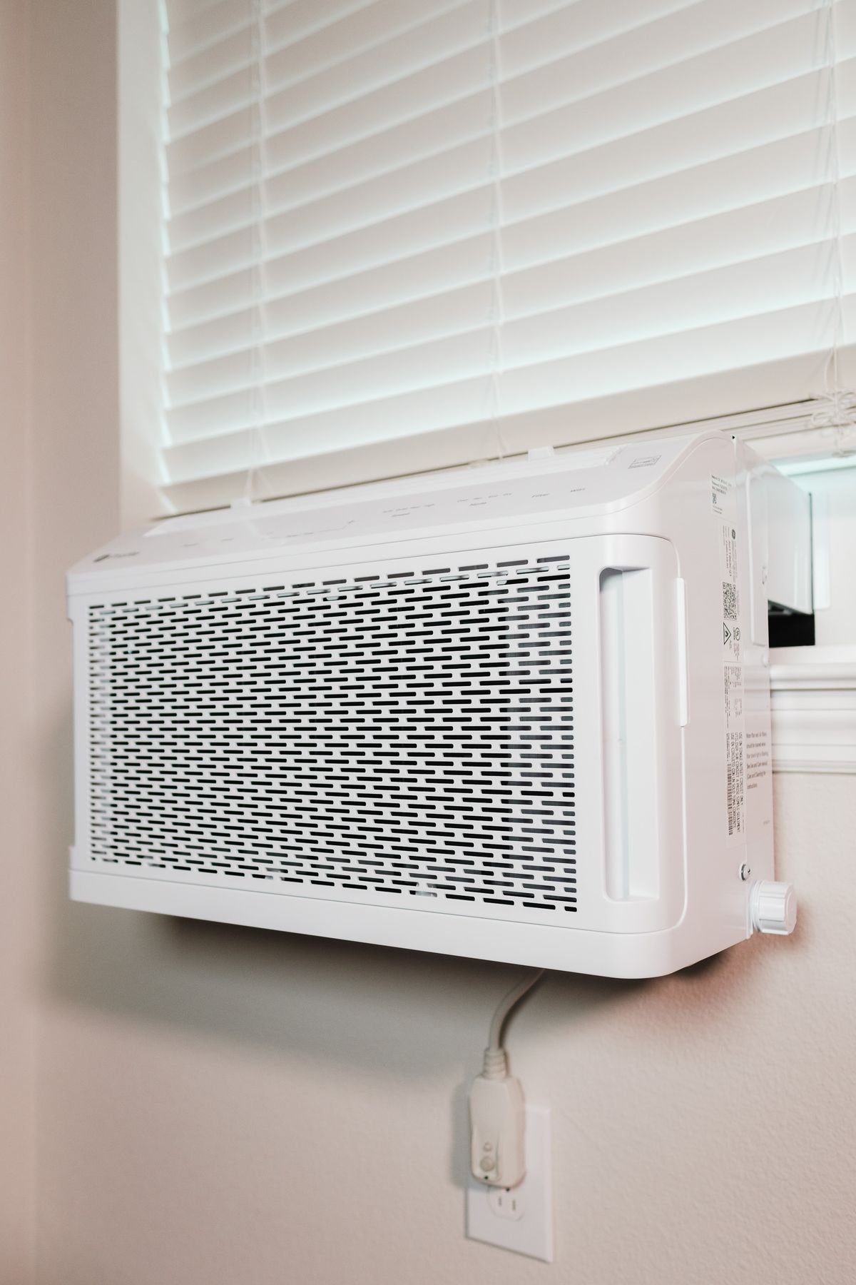 A wall-mounted air conditioning unit in a residential room, the direct-airflow source that stresses a nearby Peperomia obtusifolia