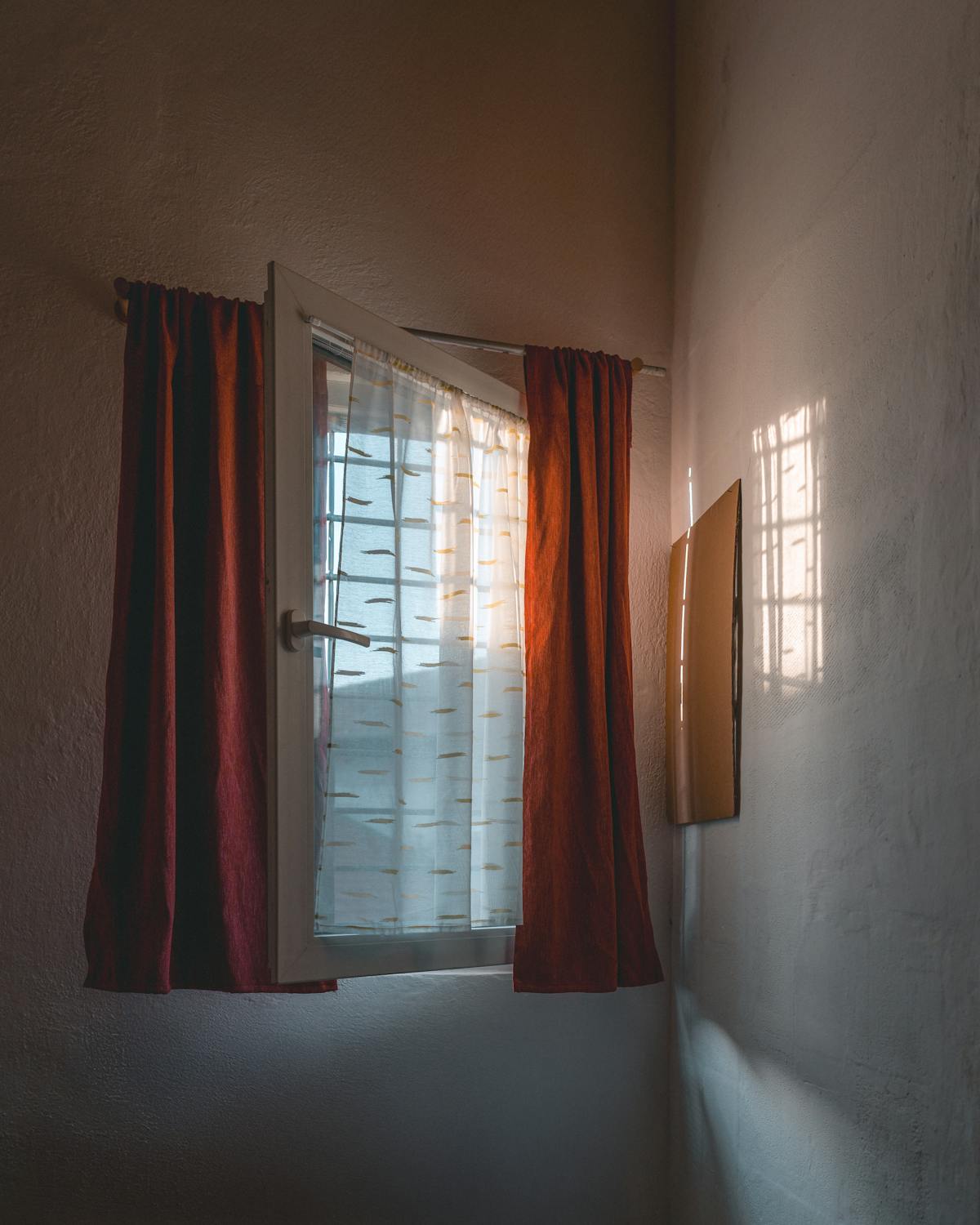 Warm sunlight streaming through a partially open window with curtains in a cozy room