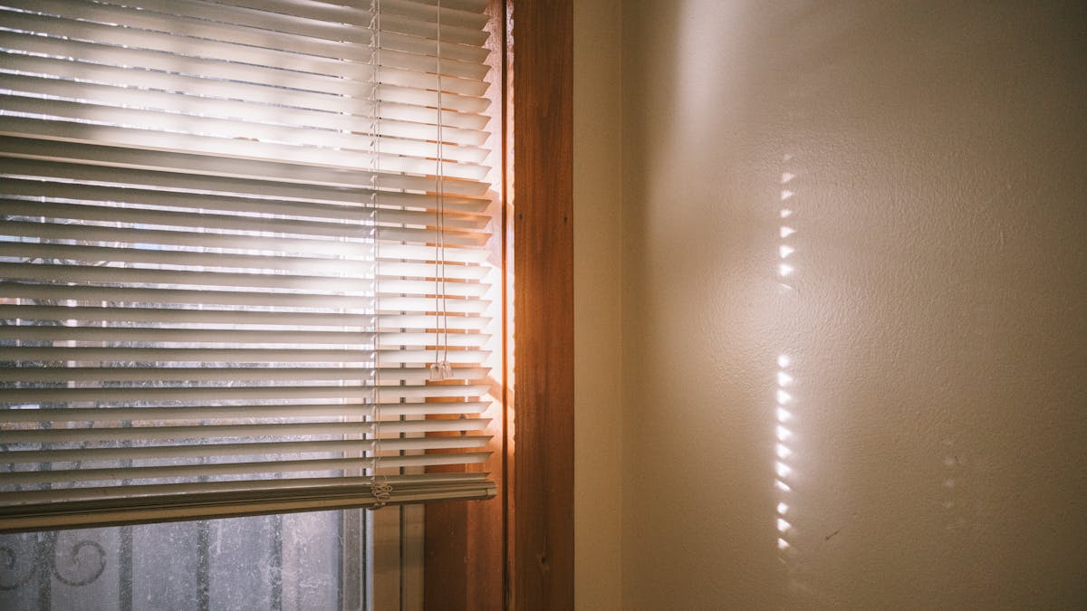 Warm sunlight casting shadows through window blinds creating a tranquil setting