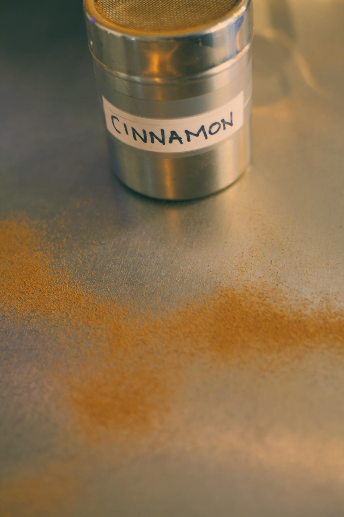 Close-up of cinnamon powder scattered near a labeled metal container