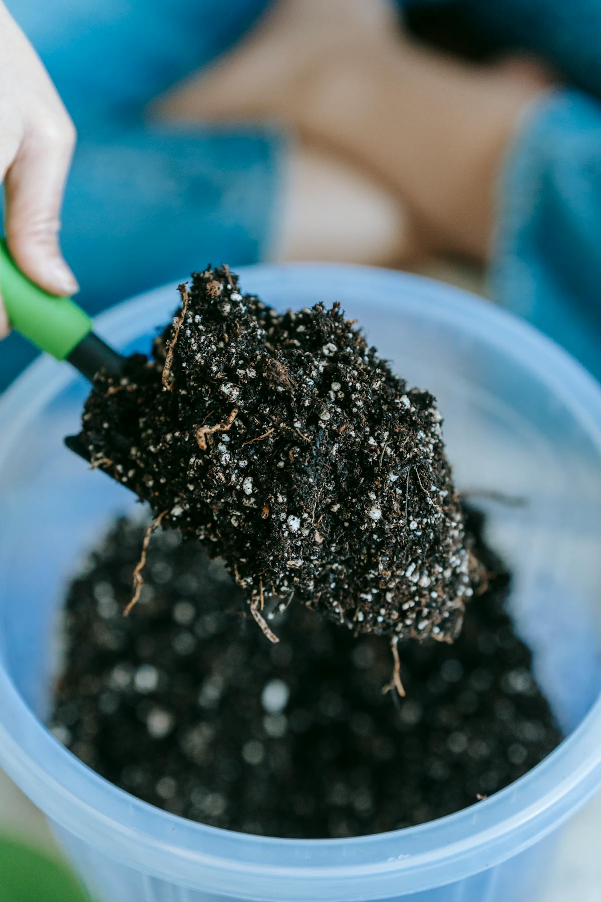 Gardener holding soil on a shovel above a container