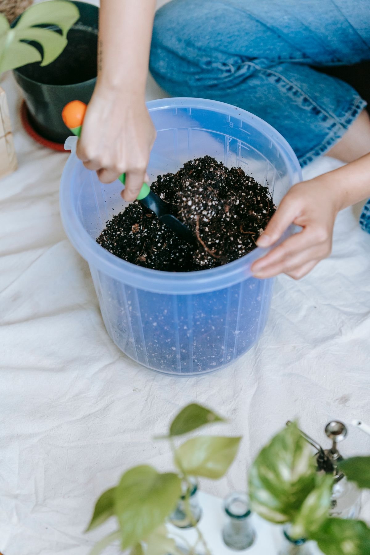 A horticulturist loosening dense, moisture-retentive compost with a trowel before amending it with perlite and bark