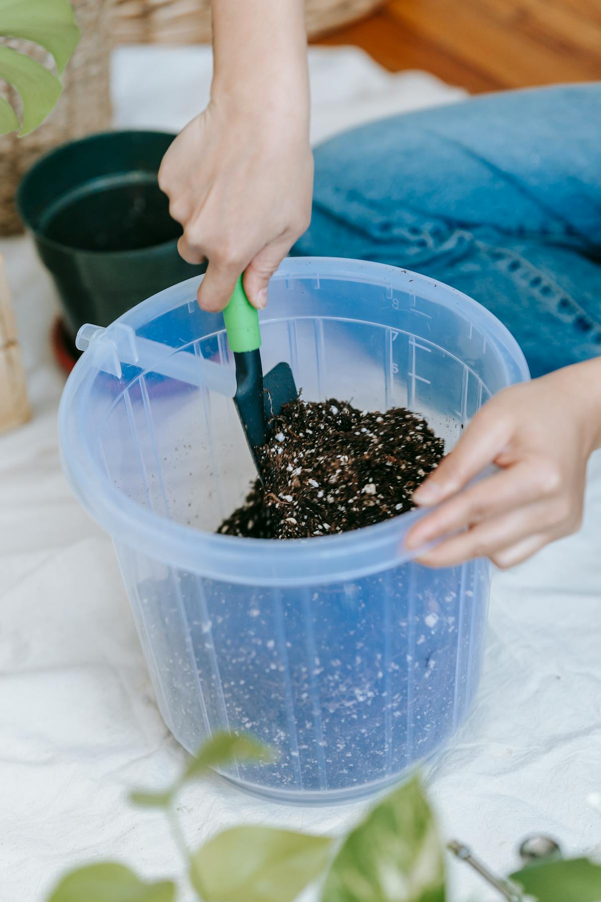 Gardener loosening soil in plastic bucket with trowel