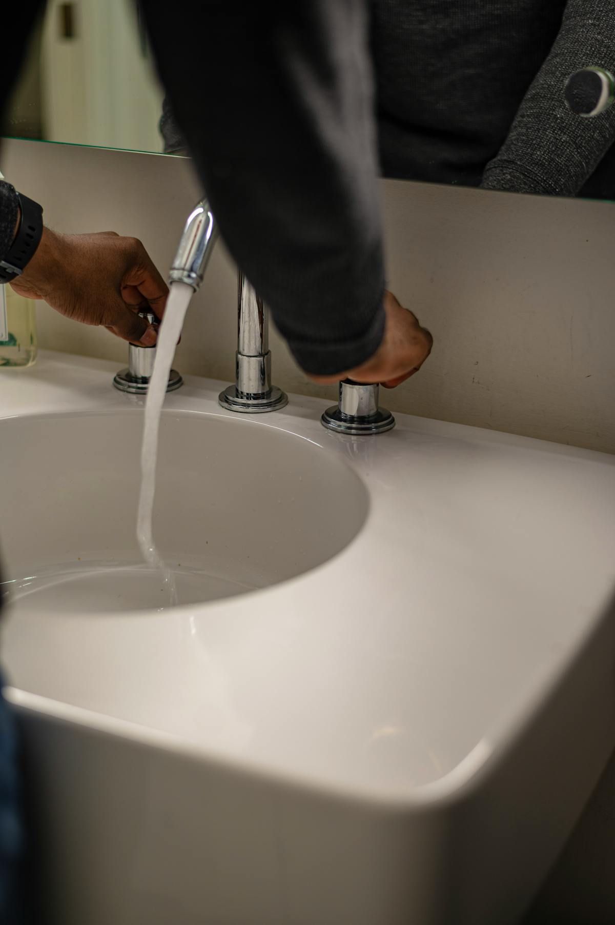 Hands adjusting a steady flow of water at a sink — the continuous low-pressure rinse that leaches accumulated salt from the root zone